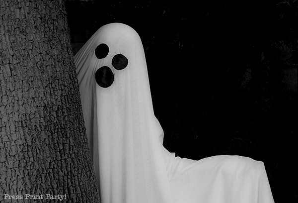 Easy ghost costume tutorial - kid in ghost costume behind tree. sheet ghost costume diy, ghost sheet, ghost costume sheet, white bed sheet, Press Print Party press print party