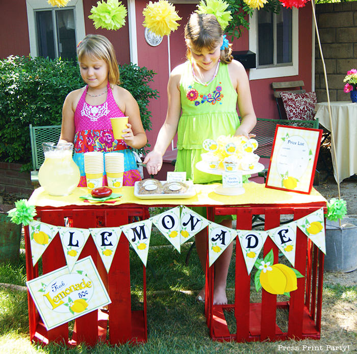 Girls with a lemonade stand. with lemonade banner price list and labels and cupcake wrappers. free printables Press Print Party!