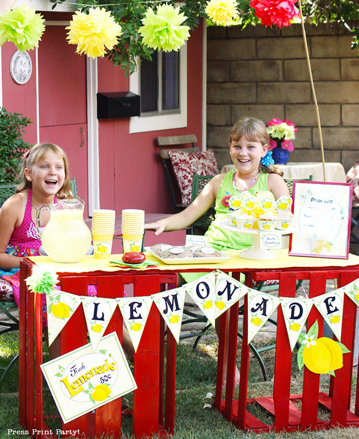 Girls with a lemonade stand. with lemonade banner price list and labels and cupcake wrappers. free printables Press Print Party!
