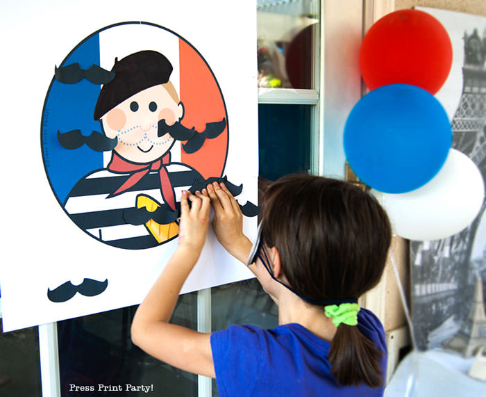 Girl playing Pin the mustache on the French guy free printable game for french or paris party. Press Print Party!