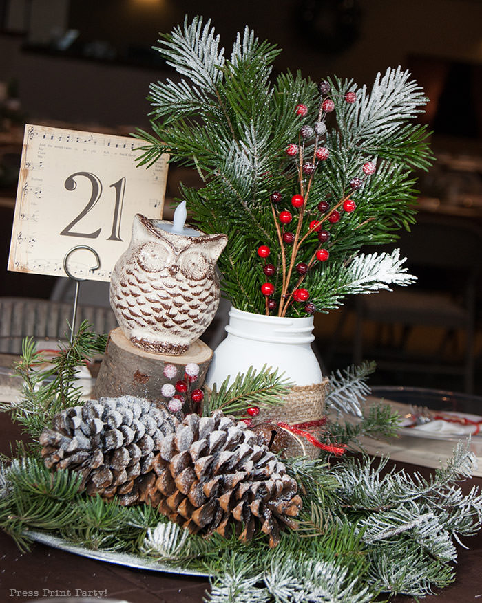 Rustic Christmas table centerpiece with greenery, rustic owl, white mason jar, pinecones, and berries. With a free music sheet table number printable download. With a brown tablecloth and music sheet place mats. Easy and cheap. by Press Print Party!