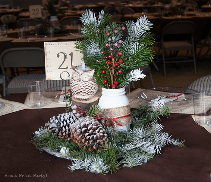 Rustic Christmas table centerpiece with greenery, rustic owl, white mason jar, pinecones, and berries. With a free music sheet table number printable download. With a brown tablecloth and music sheet place mats. Easy and cheap. by Press Print Party!