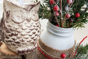 Rustic Christmas table centerpiece with greenery, rustic owl, white mason jar, pinecones, and berries. With a free music sheet table number printable download. With a brown tablecloth and music sheet place mats. Easy and cheap. by Press Print Party!