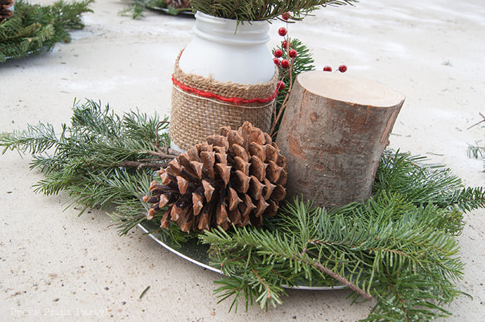 Rustic Christmas table centerpiece with greenery, rustic owl, white mason jar, pinecones, and berries. With a free music sheet table number printable download. With a brown tablecloth and music sheet place mats. Easy and cheap. by Press Print Party!