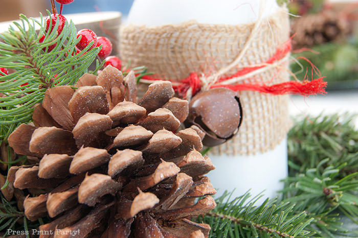 Rustic Christmas table centerpiece with greenery, rustic owl, white mason jar, pinecones, and berries. With a free music sheet table number printable download. With a brown tablecloth and music sheet place mats. Easy and cheap. by Press Print Party!