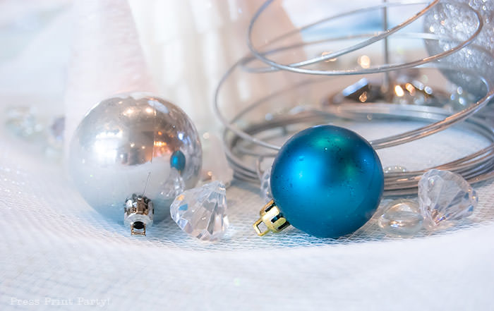 Christmas bulbs silver and blue with christmas wire tree and confetti. For Christmas table decor ideas blue and silver winter wonderland decorations. Christmas tablescape for large event christmas party, diy holiday table setting. by Press Print Party!