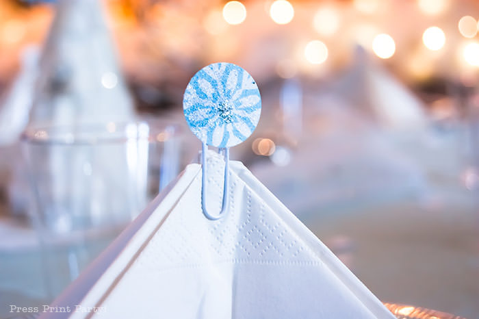 table setting with a tree napkin and a snowflake topper on a lace doily white For Christmas table decor ideas blue and silver winter wonderland decorations. Christmas tablescape for large event christmas party, diy holiday table setting. by Press Print Party!