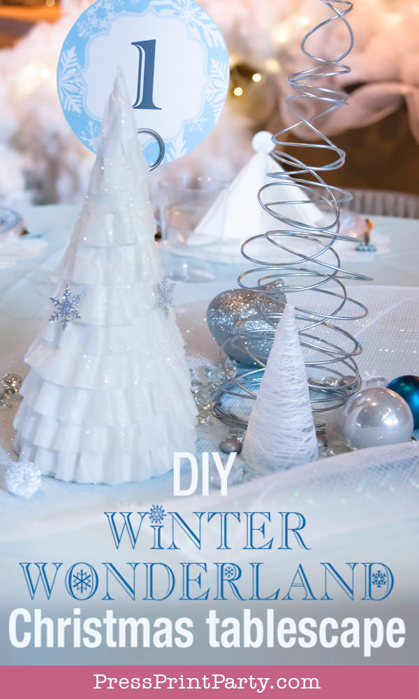 coffee filter tree, wire christmas tree and string tree on table with blue tablecloth For Christmas table decor ideas blue and silver winter wonderland decorations. Christmas tablescape for large event christmas party, diy holiday table setting. by Press Print Party!