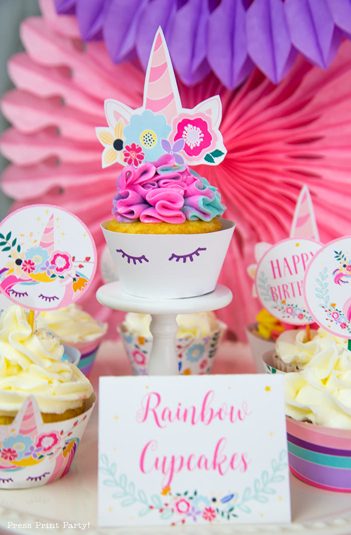 Unicorn cupcake cake with rainbow swirl frosting. Cupcake wrapper has sleepy eyes and topper has a horn with flowers.