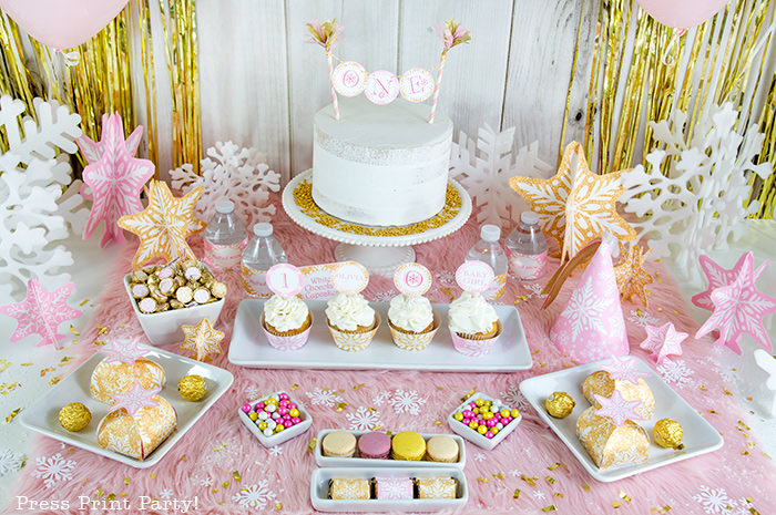 winter onderland first birthday girl party pink and gold dessert table with onederland cake and cupcakes, printable snowflakes, favor boxes and chocolate - Press Print Party!