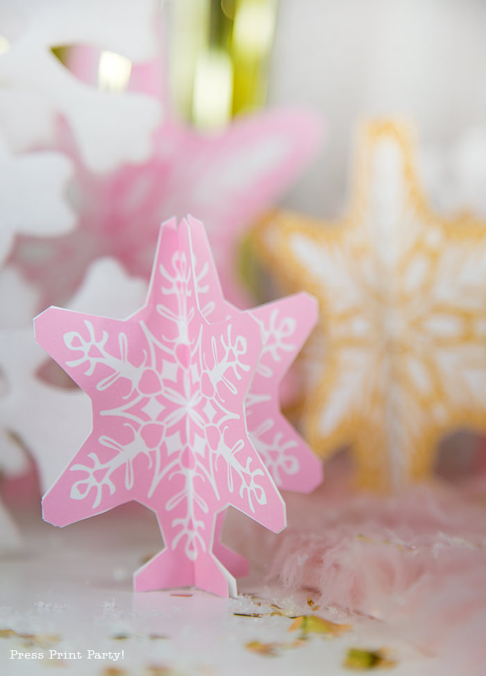 Printable 3D snowflakes in pink and gold for a girl onederland party winter onederland gold and pink snowflakes kisses with printable labels winter onderland first birthday girl party pink and gold dessert table with onederland cake and cupcakes, printable snowflakes, favor boxes and chocolate - Press Print Party!