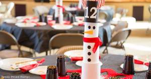 snowman made with cans on christmas table with snowman made with plates on black tablecloth - Press Print Party!