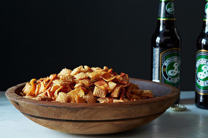 DIY chex snack mix in a wooden bowl with beer in the back