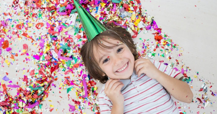 The secret to getting RSVPs to your kid's birthday party - smiling kid with birthday hat - Press Print Party!