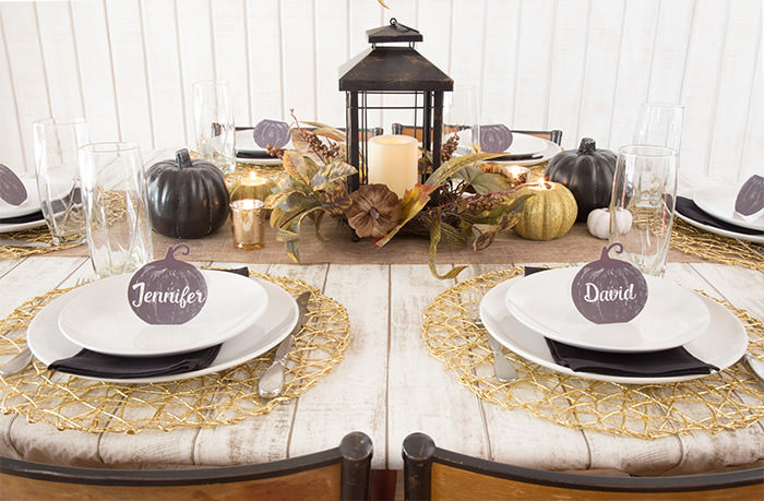 Golden Farmhouse Decorations for Thanksgiving Table. Get inspired with Thanksgiving table decor ideas. White wooden walls with gilded wreath and gold chargers, white plates, black pumpkin place cards, black lantern, golden pumpkins, votives, decorations for thanksgiving table, farmhouse decor ideas, Friendsgiving ideas, thanksgiving table decor, Thanksgiving table setting - tablescape. Press Print Party!