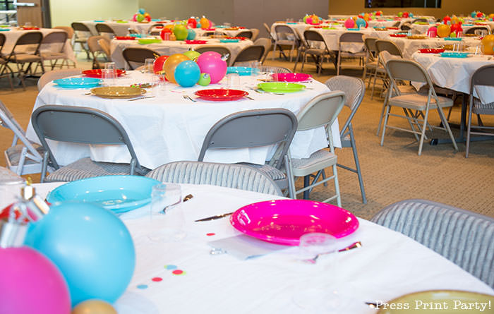 Christmas table centerpiece. Balloons with ornament toppers in green, gold, blue, red and hot pink. Christmas tablescape balloon centerpiece decoration with large ornament balloons and plates that look like ornaments. Very cheery and bright. Fun and creative for your Christmas party. Simple Christmas balloon decor ideas diy.