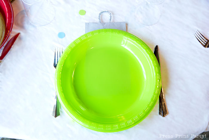 close up of green plate with silver napkin to look like an ornament. Christmas tablescape balloon centerpiece decoration with large ornament balloons and plates that look like ornaments. Very cheery and bright. Fun and creative for your Christmas party. Simple Christmas balloon decor ideas diy. Press Print Party!