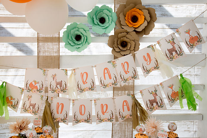 Woodland baby shower banner printable with paper flowers backdrop with white wood and burlap. Woodland animals Baby Shower Theme with woodland creatures and forest animals party supplies. Woodland decoration girl baby shower ideas. Can be used for woodland birthday party. Rustic forest animals with flowers and antlers. Fox baby shower, Deer baby shower.