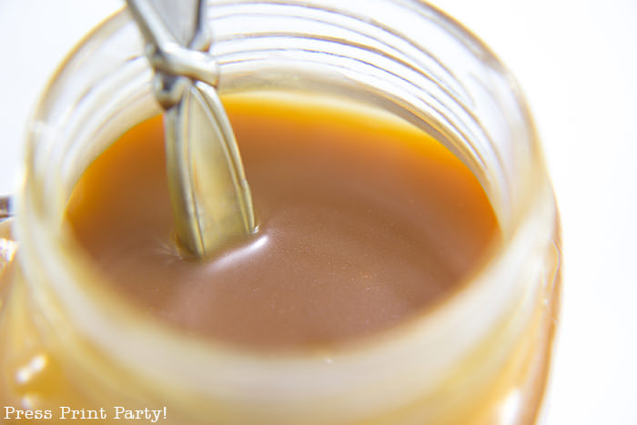 Caramel sauce in mason jar with spoon.How to make a caramel sauce easy recipe for dip or toffee cake or pudding