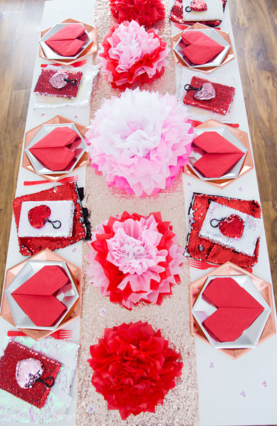 Galentines day or valentines day table decorations with tissue paper flowers in pink and red and red heart napkins and flip sequins favors - Galentine's Day Party Ideas for Teens - Press Print Party!