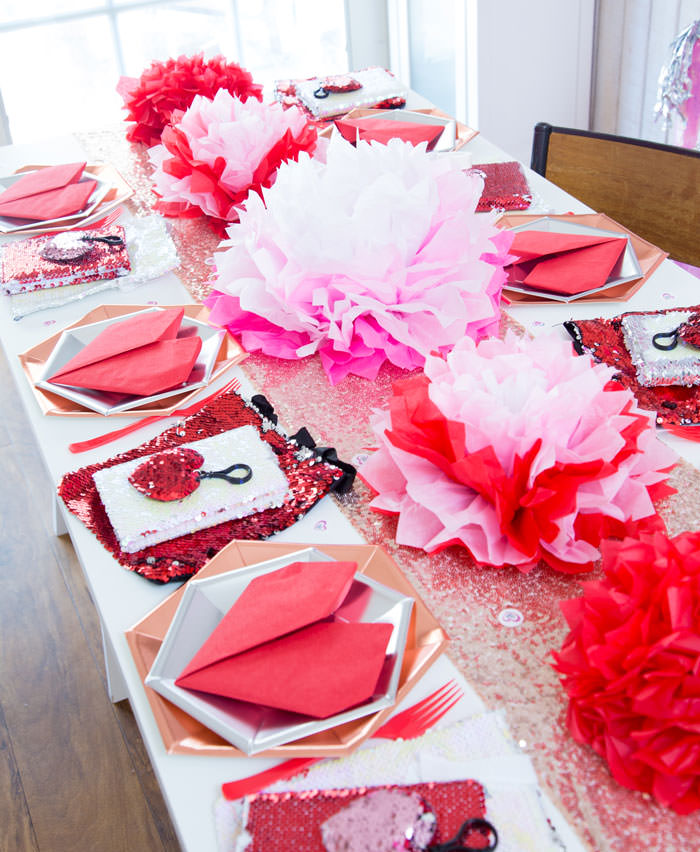 Galentines day or valentines day table decorations with tissue paper flowers in pink and red and red heart napkins and flip sequins favors - Galentine's Day Party Ideas for Teens - Press Print Party!