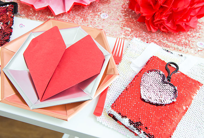 Red heart napkin fold on rose hexagonal metallic plate and silver plate -Flip sequins bag with flip sequins notebook and flip sequins heart clip keychain as party favor ideas- Galentine's Day Party Ideas for Teens - Press Print Party!