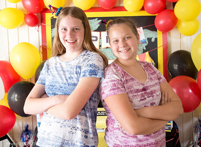 2 birthday girls in front of backdrop - The amazing race party ideas - Press Print Party!