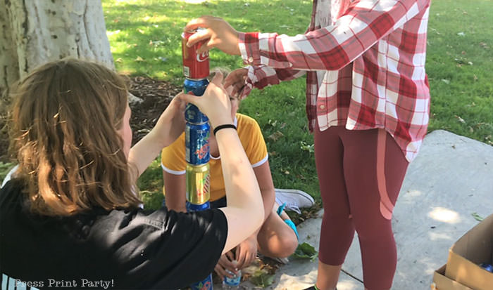 stacking empty cans as part of an amazing race party challenge - press print party