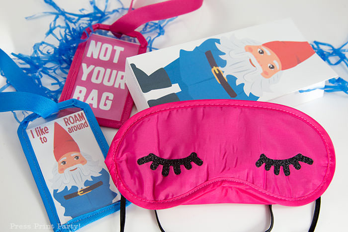 Amazing Race Party Favor Bags with sleep mask with eyelashes and 2 luggage tags, one with a roaming gnome that says I like to roam around and one with Not Your Bag in pink. Press Print Party!