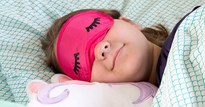 sleeping girl with eye mask with eyelashes and unicorn pillow