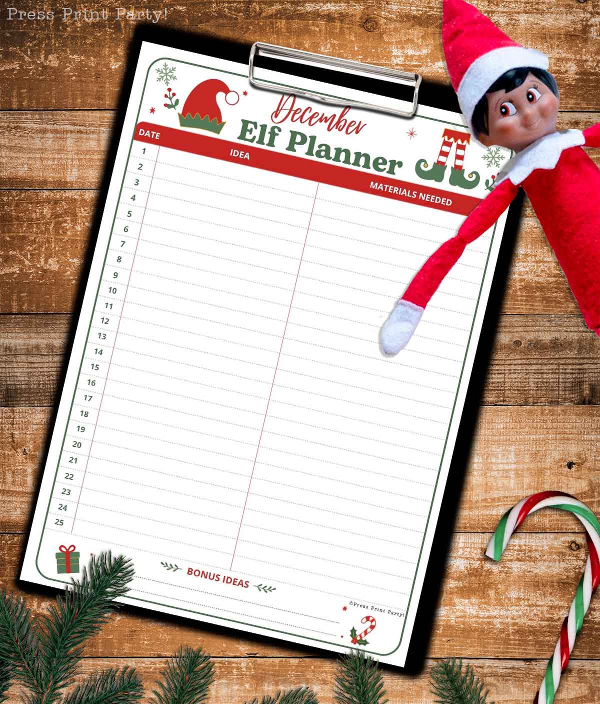 A festive βElf Plannerβ sheet, designed as an elf on the shelf printable, rests on a clipboard with dates, ideas, and materials columns, lying on a wooden surface with a candy cane and a smiling elf doll in the top right corner.