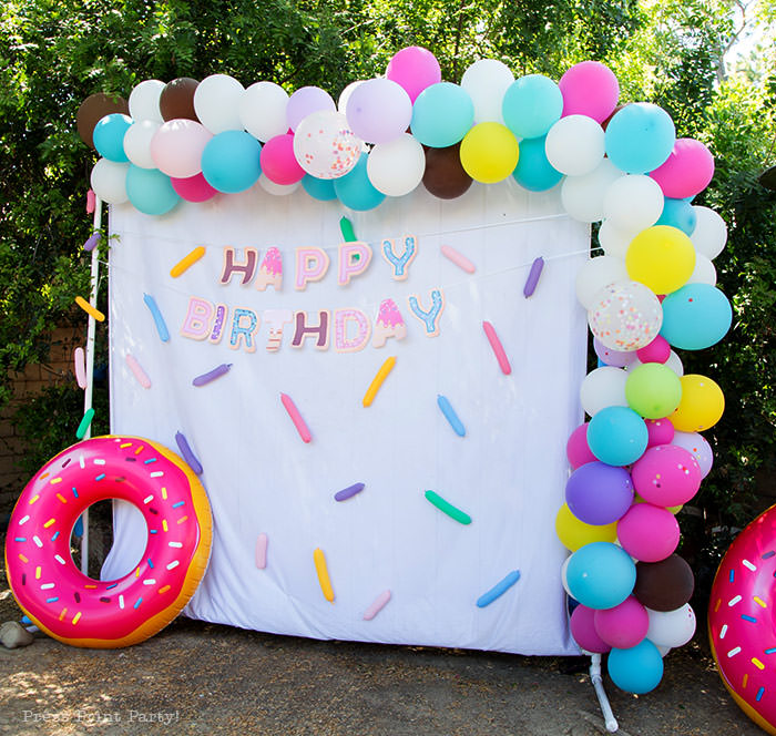 Donut party ideas donut photobooth with balloon garland and happy birthday banner and confetti. Press Print Party