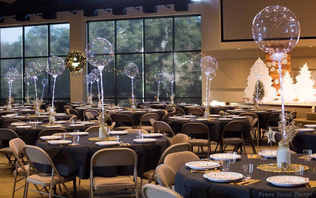 many tables with light up balloons in sanctuary for Christmas dinner.How to set up a sparkling christmas banquet with LED Bobo balloons with string lights. Press Print Party!