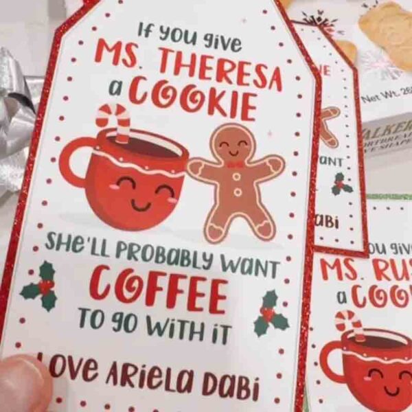 A festive tag with a cheerful cookie and gingerbread man illustration reads, "If you give Ms. Theresa a cookie, she'll probably want coffee or even a chip bag to go with it. Love Ariela Dabi." Product: Kids Valentine Chip Bag Tag Pink, I ❤ Our Friend-chip.