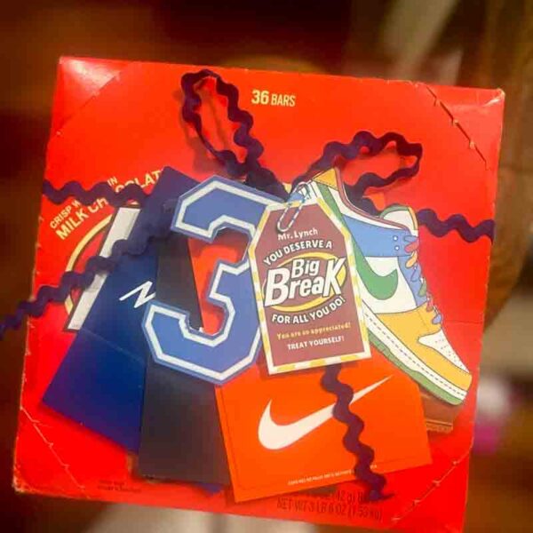 A decorated box of 36 chocolate bars has a red background with a sneaker illustration, tags like a large "3" and Nike logos. It resembles vibrant chip bag designs, similar to the Kids Valentine Chip Bag Tag Pink, I ❤ Our Friend-chip. Curly blue ribbon adds festive flair.