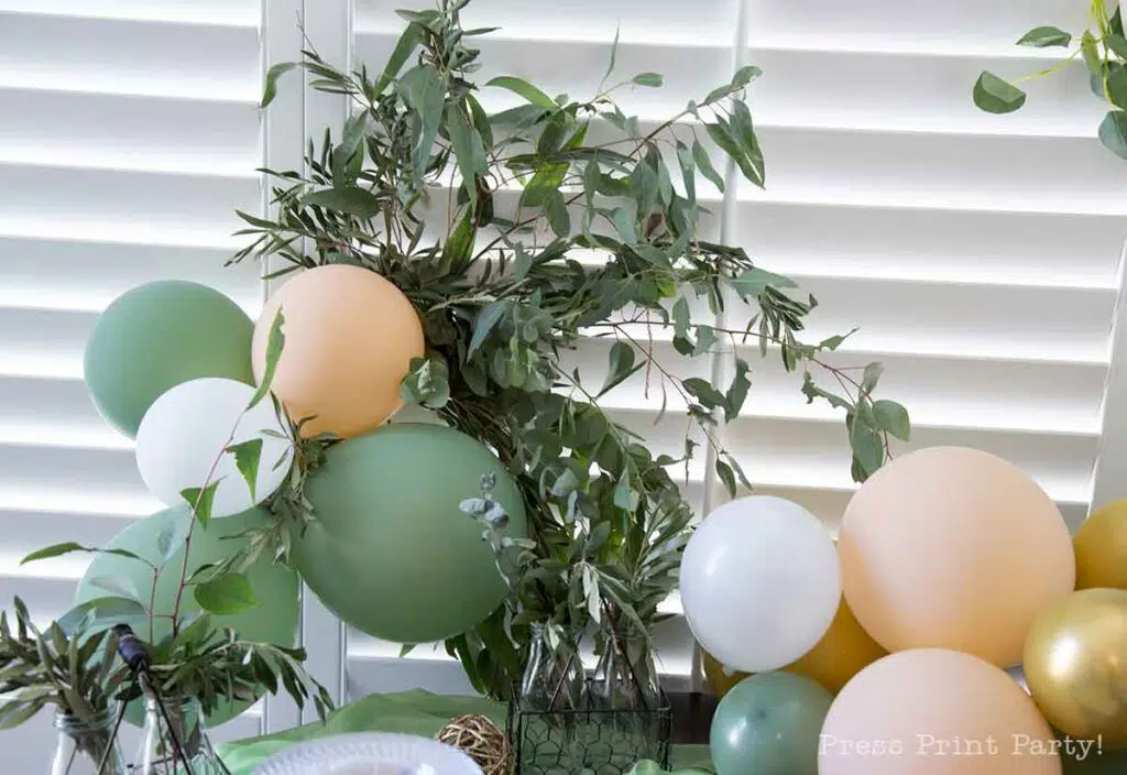 Greenery baby shower decor ideas with printable banner and eucalyptus on table and balloons peach and green - Press Print Party!