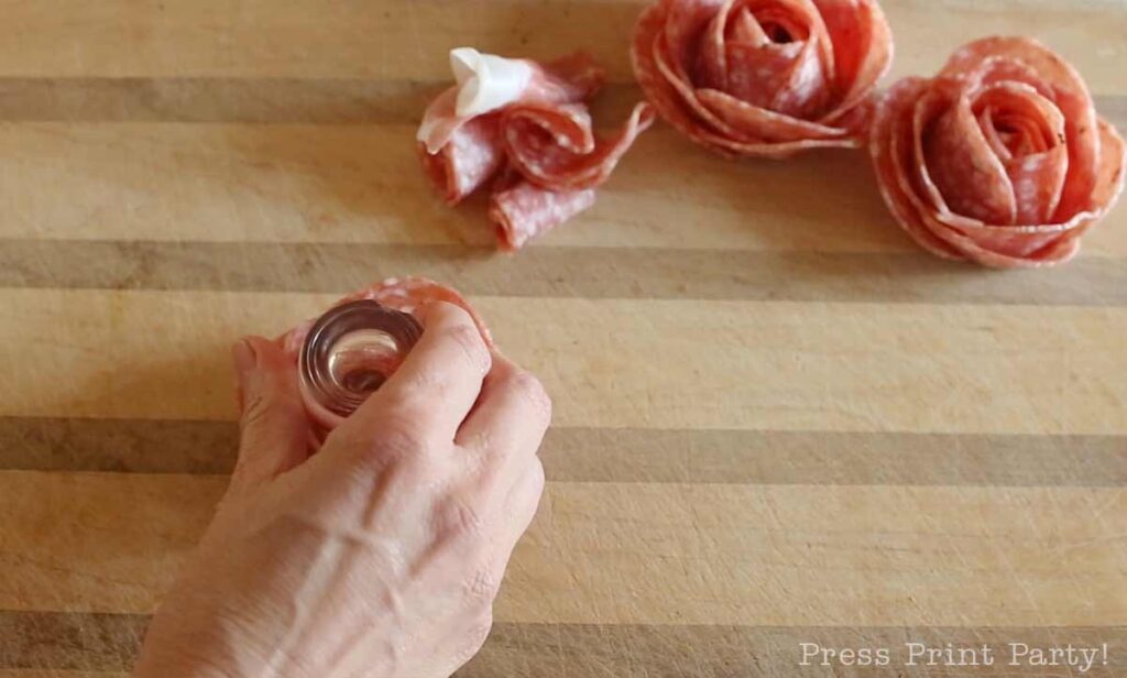 turning the shot glass over -how to make a salami rose for your charcuterie board - Press Print Party