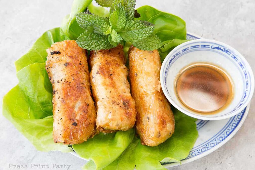 fried vietnamese egg rolls on plate with dip mint and lettuce- How to make vietnamese egg rolls recipe cha gio nem ran - Press Print Party!