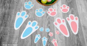 free printable easter bunny footprints and stencils in 2 sizes and 2 colors blue and pink. with Easter basket on grey floor - Press Print Party!