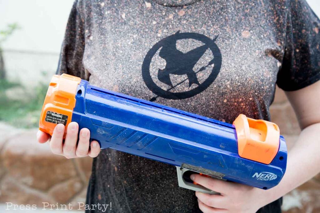 nerf tennis ball gun as part of a challenge on the scavenger hunt - 5 creative hunger games party activities and games with scavenger hunt and free printables. press print party!