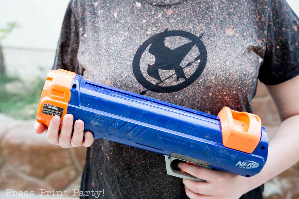 nerf tennis ball gun as part of a challenge on the scavenger hunt - 5 creative hunger games party activities and games with scavenger hunt and free printables. press print party!