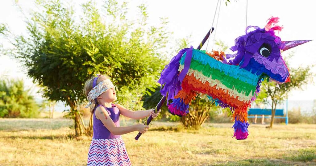 little girl wacking a pinata -15 fun birthday party activities for toddlers and young kids - Press Print Party!