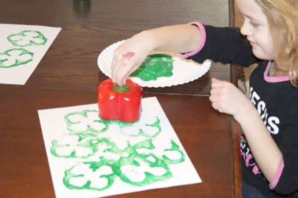 girl stamping shamrocks with a red pepper