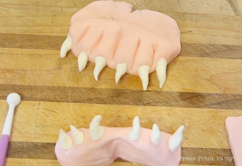 top and bottom gums with teeth made with fondant for the monster book of monsters cake on table - Press Print