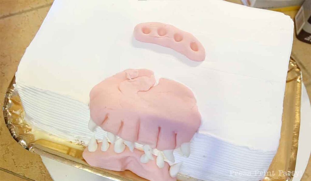 putting the fondant pieces on the monster book of monsters cake on table - Press Print