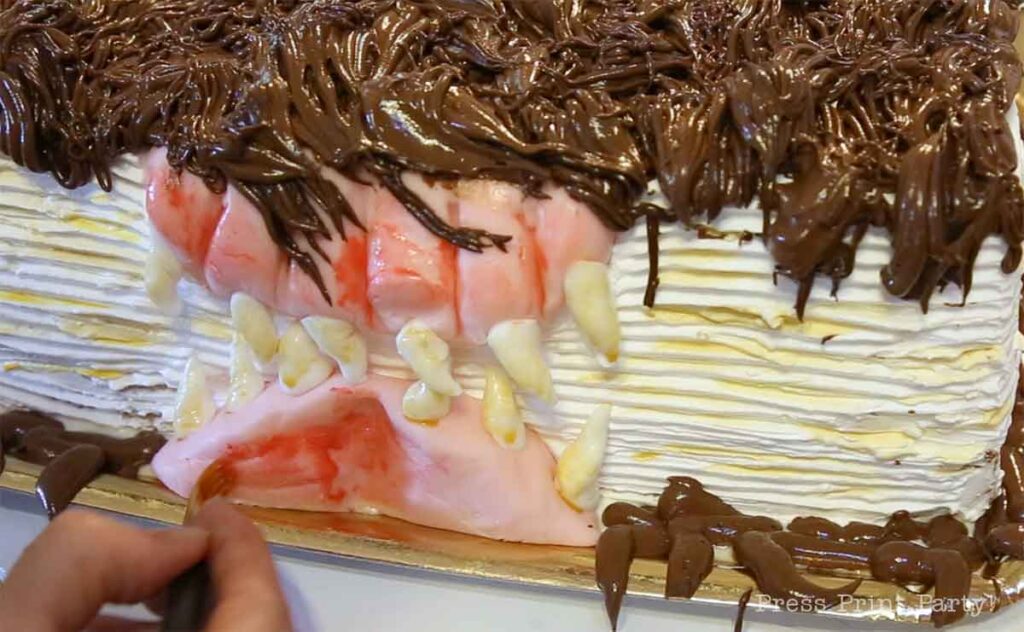close up of painting the gums on the monster book of monsters cake on table - Press Print Party