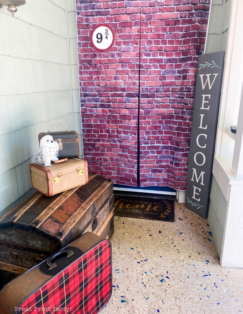 Harry potter party entrance with 9 and three quarters brick wall, hedwig and suitcases.