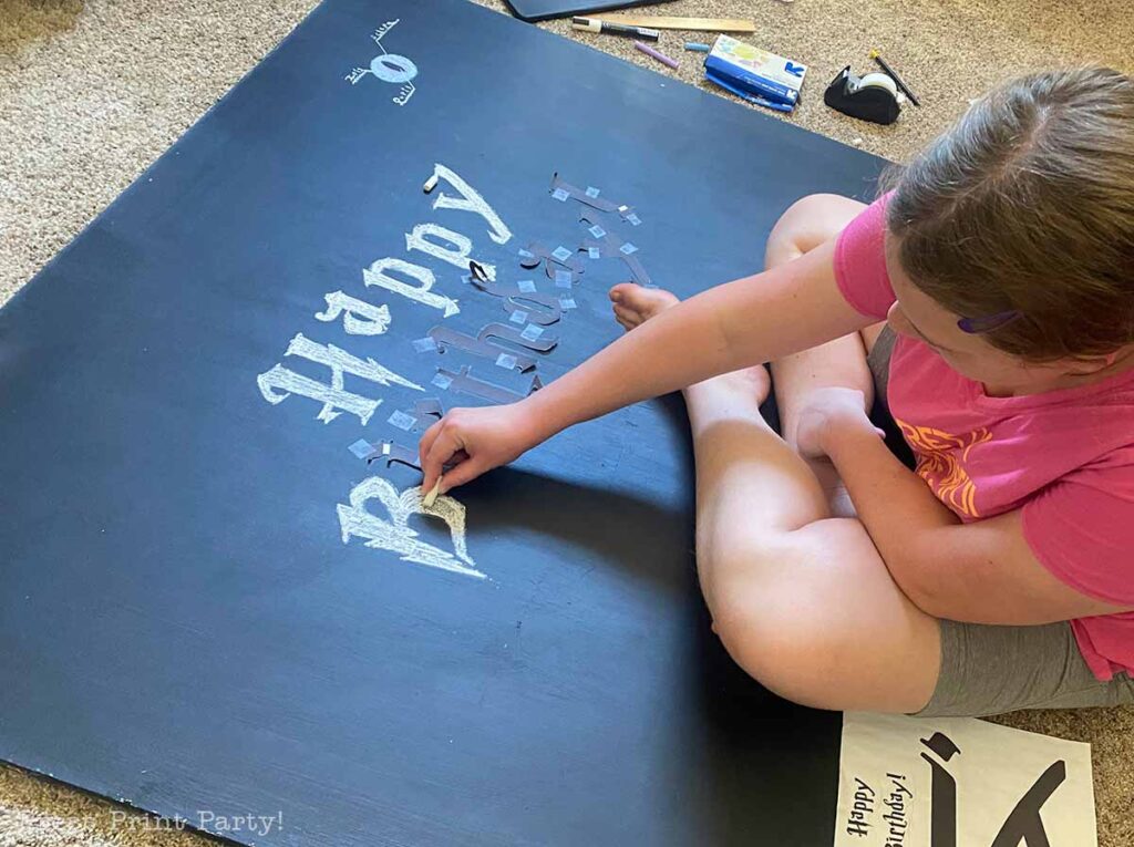 girl making the chalboard backdrop for a Harry Potter party