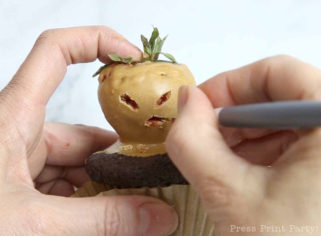 making a mandrake face with a blade on the mandrake cupcake
