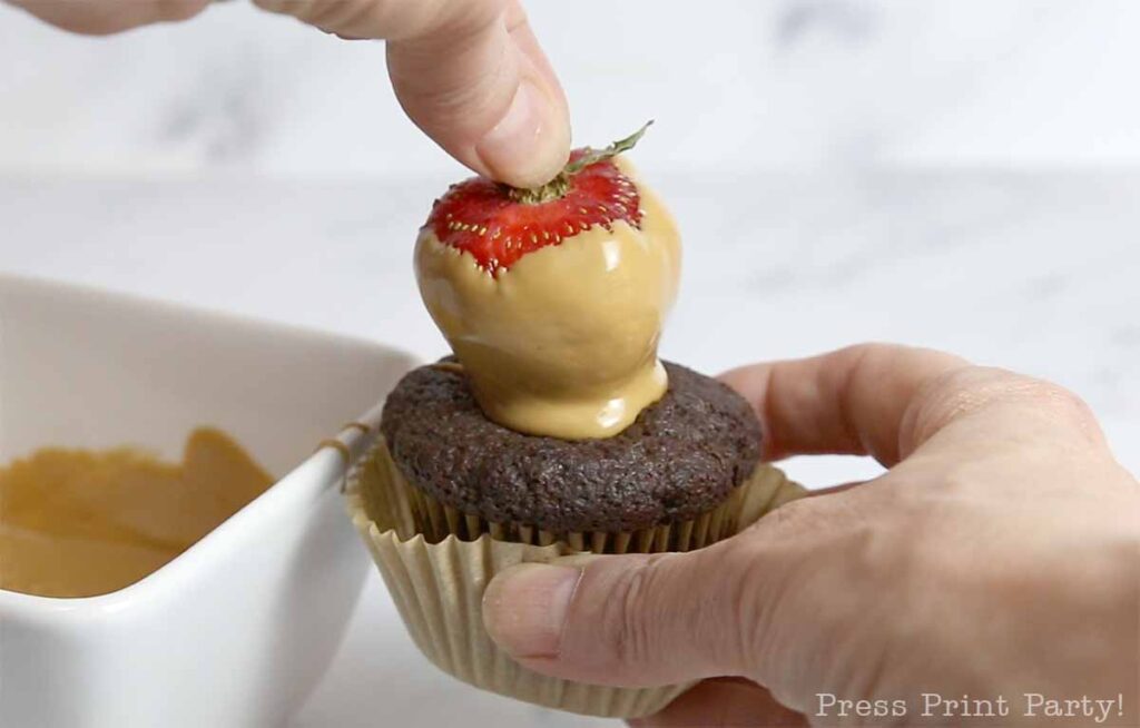 strawberry in candy melt on top of a chocolate cupcakes